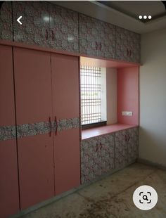 an empty room with pink cupboards and window