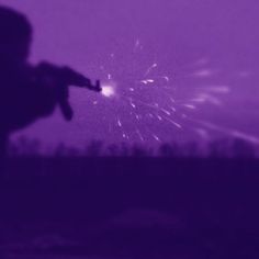 the silhouette of a person holding a firework in their hand and looking at it