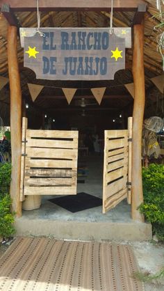 the entrance to an open air restaurant with wooden doors and stars hanging from it's roof