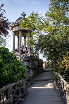 people are standing at the top of a stone structure with trees and bushes around it