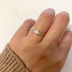 a woman's hand with a pearl ring on it