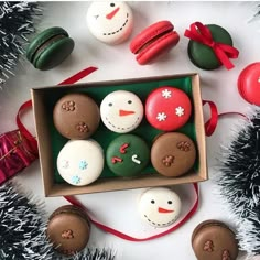 a box filled with different types of decorated doughnuts next to christmas decorations and tinsel