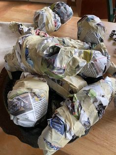 a wooden table topped with lots of paper wrapped around balls of newspaper on top of it