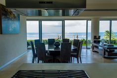 a dining room table and chairs in front of large windows with the ocean out side