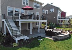 a patio with an umbrella and couches in front of a house on the lawn