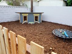 a backyard with a trampoline and dog house in the back yard, next to a fence