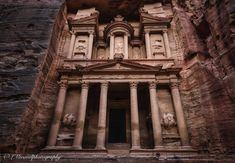 an ancient building built into the side of a mountain with columns and carvings on it