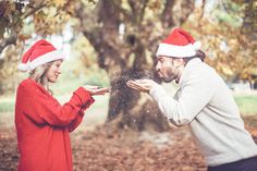 a man and woman in santa hats are throwing snow into each other's hands