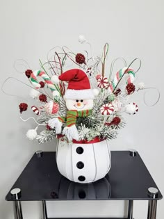 a vase filled with candy canes and a snowman decoration on top of a table