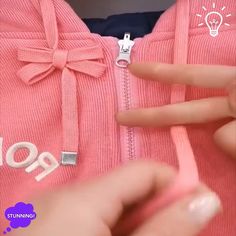 a person is holding onto a pink sweater with a bow on the front and bottom