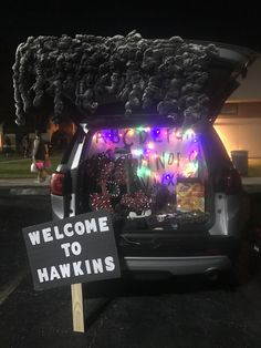 a welcome to hawks sign in the back of a car with its trunk open and it's lights on