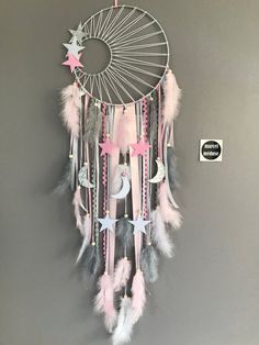 a dream catcher with pink, grey and white feathers