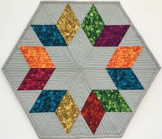 a multicolored hexagonal quilt on a white background with gold sequins