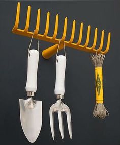 three forks and two knives hanging on a wall next to a yellow handled knife holder