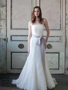 a woman standing in front of a door wearing a dress with a bow on it