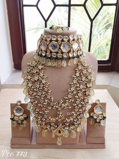 an elaborate necklace and earring set on display in front of a window with windows