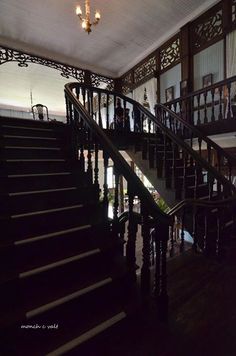 the stairs are made of wood and have wrought iron handrails, with chandeliers hanging from them