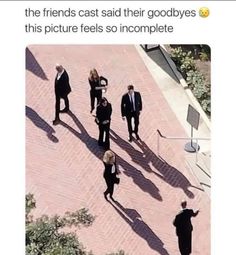 a group of people walking down a sidewalk next to each other on top of bricks