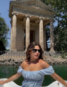 a woman sitting on the back of a boat in front of a building with columns