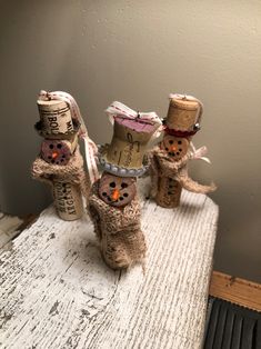 three snowmen made out of wine corks sitting on top of a wooden table