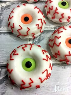 four donuts with white frosting and red sprinkles decorated to look like eyes