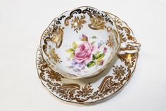 an antique tea cup and saucer with gold trimmings on a white background