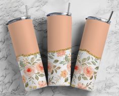 three tumbles with floral designs on them sitting on a marble countertop next to each other