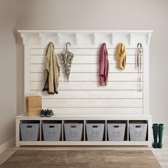 a white bench with baskets and umbrellas hanging on the wall next to two coats rack