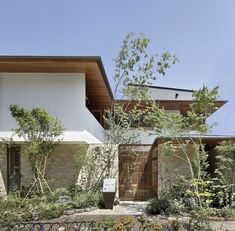 the house is surrounded by trees and plants, with a fence around it that leads to an entrance