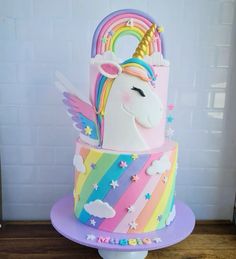 a multi - colored cake with a rainbow unicorn on top and stars around the edges