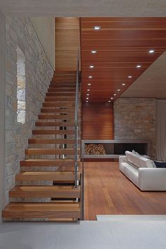 a living room filled with furniture next to a fire place under a stair case on top of a hard wood floor