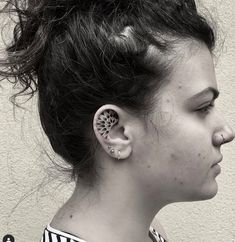 a woman with ear piercings on her ears looking to the side in black and white