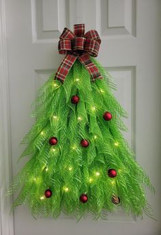 a christmas tree shaped door hanger with lights on it's side and a plaid bow