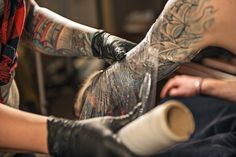 a man getting his tattoo done by another person with tattoos on their arm and leg