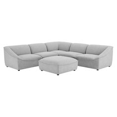 a grey sectional couch sitting on top of a white floor next to a footstool