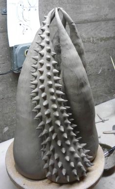 two clay vases sitting on top of a table next to each other, one with spikes