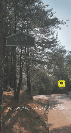 a street sign on the side of a road near some trees and bushes with writing in arabic