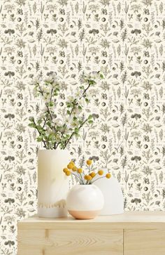 two vases with flowers are sitting on a dresser next to a wallpapered background