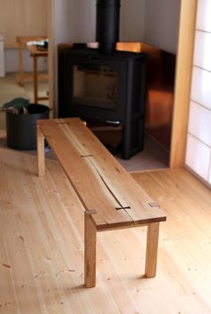 a wooden bench sitting on top of a hard wood floor next to a fire place