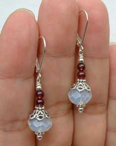 a pair of earrings with beads and charms on the end of them, sitting in someone's hand