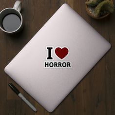 i love horror sticker on a table next to a cup of coffee and pen