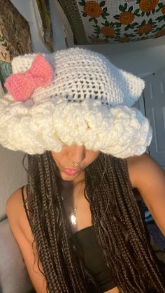 a woman wearing a white crochet hat with a pink bow on it's head