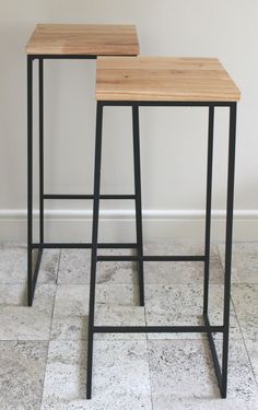 two black metal and wood bar stools against a white wall