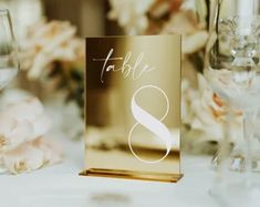 the table numbers are placed on top of each other in front of some wine glasses