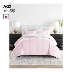 a bed with pink comforter and pillows on top of it in front of a white wall