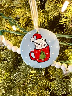 a christmas ornament hanging from the tree with santa clause on it's cup