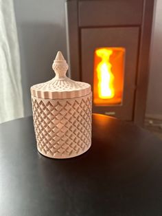 a small jar sitting on top of a table next to a fire burning in the fireplace