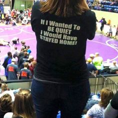 a woman standing on top of a basketball court in front of an arena filled with people