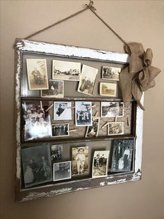 an old window frame with pictures hanging on the wall and a bow attached to it