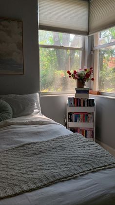 a bed sitting next to a window in a bedroom with books on top of it